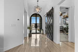 Entryway with a barn door, light wood-style floors, a high ceiling, and hanging lights