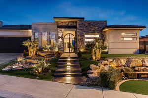 View of front of house with stone siding, stucco siding, an attached garage, and driveway
