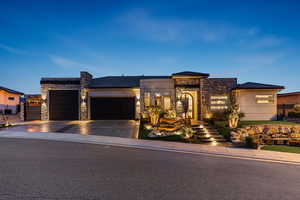View of front of house featuring stone siding, a garage, driveway, and stucco siding