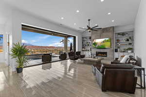 Living room with built in features, ceiling fan, light wood-style floors, a fireplace, and recessed lighting