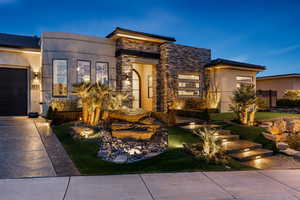View of front of home with stone siding, stucco siding, concrete driveway, and a garage
