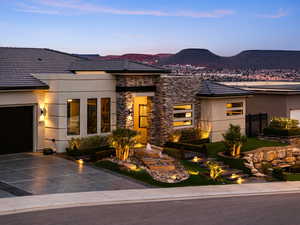 View of front of home featuring stucco siding, an attached garage, a mountain view, driveway, and stone siding