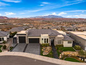 View of front facade featuring stone siding, a garage, a residential view, and a mountain view