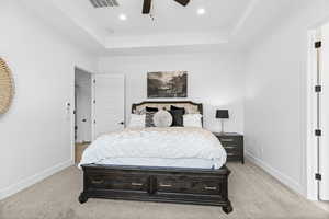 Bedroom featuring a tray ceiling, ceiling fan, light colored carpet, and recessed lighting