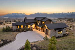 View of front of home with stone siding, concrete driveway, a chimney, and a mountain view