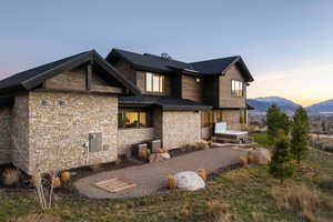 Back of house at dusk with a standing seam roof, stone siding, and a mountain view