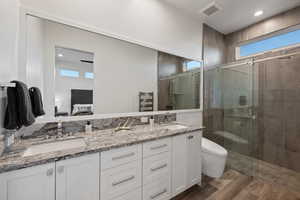 Ensuite bathroom with double vanity, a stall shower, a towel warmer, recessed lighting, and light wood finished floors