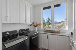 Laundry room with cabinet space, separate washer and dryer, and a mountain view