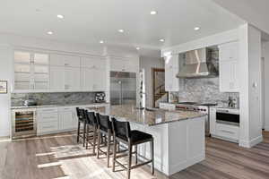 Kitchen featuring a breakfast bar, recessed lighting, light stone counters, wine cooler, and high quality appliances