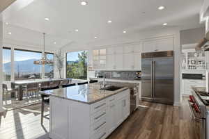 Kitchen with glass fronted cabinets, white cabinetry, a mountain view, premium appliances, and pendant lighting