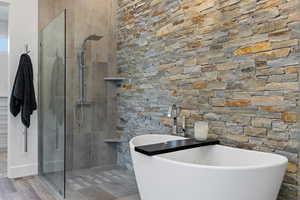 Full bathroom featuring walk in shower, a freestanding bath, and wood finished floors