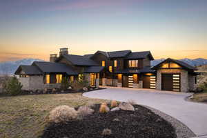 View of front facade with stone siding, a standing seam roof, a mountain view, concrete driveway, and a chimney