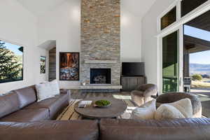 Living area with plenty of natural light, a fireplace, wood finished floors, and lofted ceiling