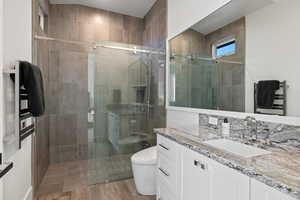 Full bathroom with vanity, a shower stall, a towel warmer, and light wood-style flooring