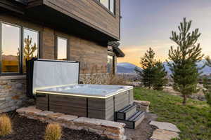 Patio terrace at dusk with a hot tub, a mountain view, and grilling area