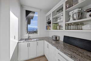 Bar with white cabinets, light stone counters, a mountain view, and light wood-type flooring