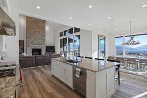 Kitchen featuring white cabinets, vaulted ceiling, stainless steel appliances, light stone counters, and dark wood finished floors