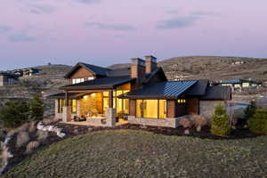 Back of property with stone siding, a standing seam roof, a patio area, and a mountain view