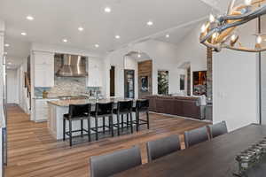 Kitchen featuring white cabinetry, light stone counters, light wood-type flooring, vaulted ceiling, and open floor plan