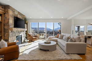 Living room featuring a stone fireplace, wood finished floors, and recessed lighting