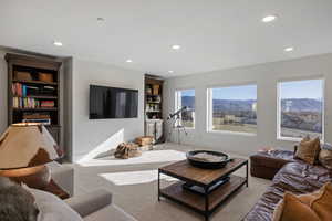 Carpeted living room with built in shelves and recessed lighting