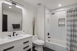 Bathroom featuring shower / bath combination with curtain, vanity, and recessed lighting