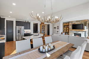 Dining room featuring light wood-style floors, suspended lighting, a fireplace, and built in shelves