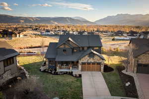 View of front of property with covered porch, stone siding, driveway, a mountain view, and a residential view