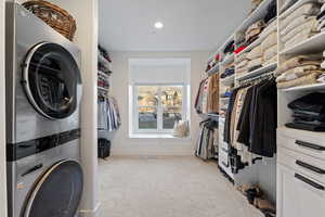 Laundry area with stacked washer / drying machine, light carpet, and recessed lighting