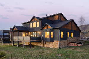 Back of property featuring stone siding, board and batten siding, and a yard