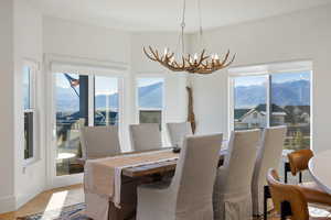 Dining space with a mountain view, suspended lighting, healthy amount of natural light, and wood finished floors