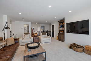 Carpeted living room with recessed lighting and built in shelves