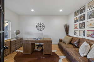 Office space with light wood-style flooring and recessed lighting