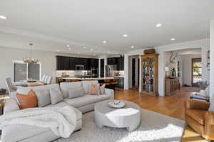 Living room with light wood-type flooring and hanging lights