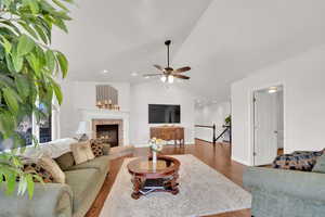 Living room featuring wood floors, a ceiling fan, lofted ceiling, a tile fireplace, and recessed lighting