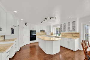 Kitchen with backsplash, glass fronted cabinets, white cabinets, a kitchen island, appliances