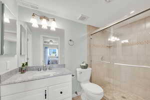 Ensuite bathroom featuring vanity, a stall shower, and a ceiling fan