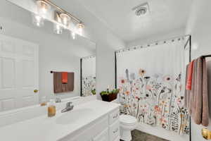 Bathroom with vanity, a textured ceiling, and shower / bath combo