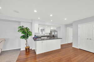 Basement Kitchen featuring white cabinets, dark stone counters, a peninsula, stainless steel fridge with ice dispenser, and recessed lighting