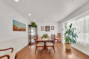 Dining room with wood floors, recessed lighting, and ornamental molding