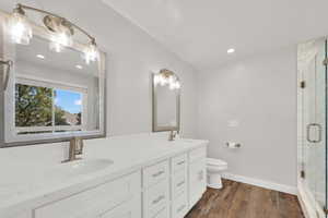 Primary Bathroom featuring double vanity, a stall shower, dark wood-type flooring, and recessed lighting