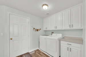 Laundry room featuring cabinet space, light wood-type flooring, and independent washer and dryer