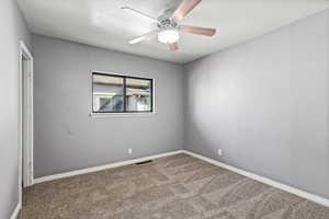 Carpeted spare room featuring ceiling fan and baseboards