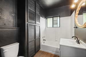 Full bath featuring a textured wall, vanity, dark wood-style floors, a closet, and shower / tub combination