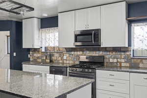 Kitchen with white cabinetry, dark stone countertops, and stainless steel appliances
