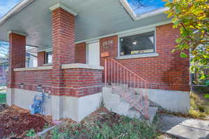 Entrance to property featuring brick siding and a porch