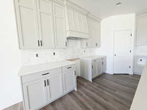 Kitchen featuring dark wood finished floors, tasteful backsplash, and white cabinets