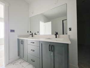 Bathroom with double vanity and light marble finish flooring