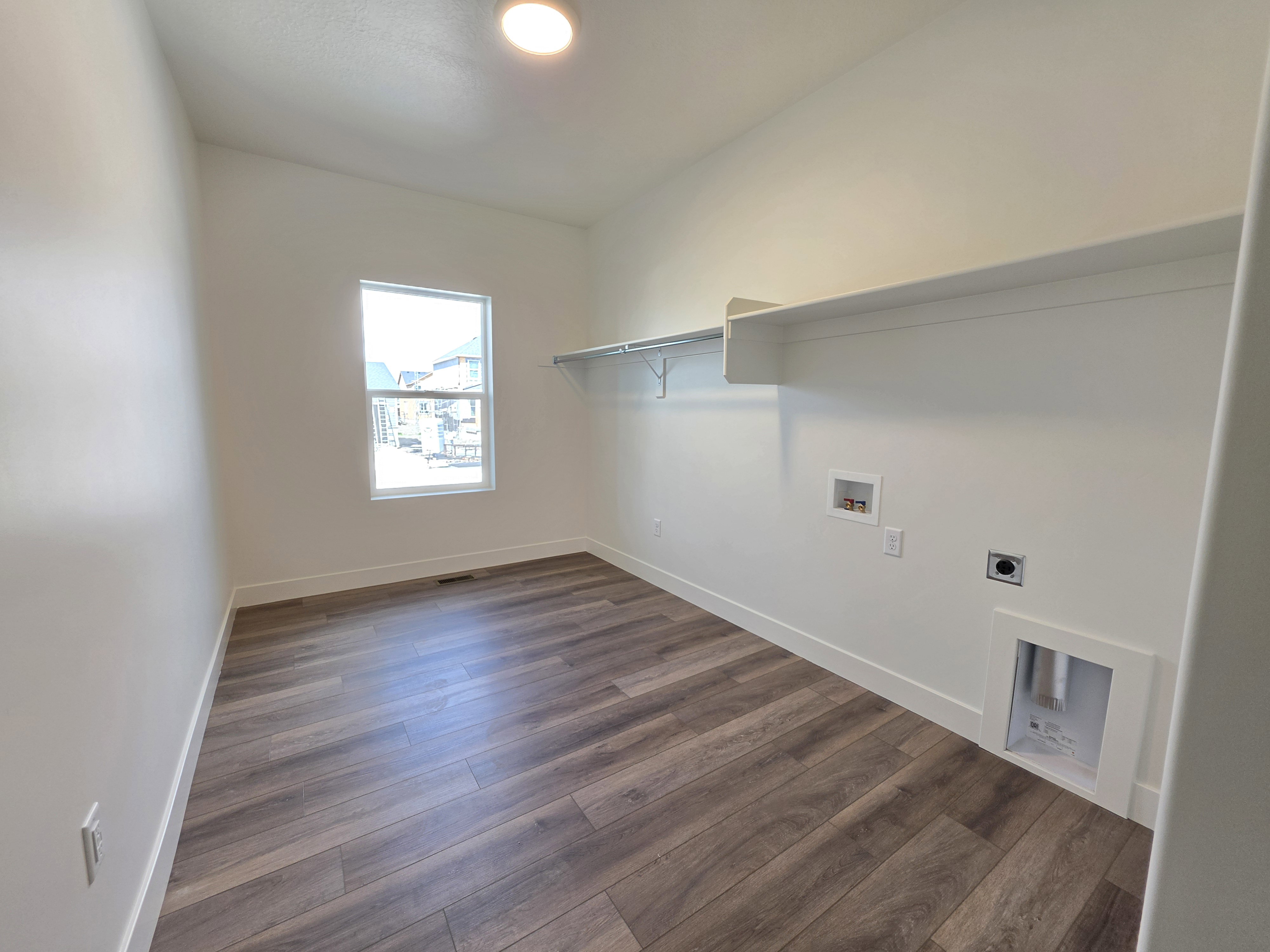 Laundry room with wood-finish flooring, a window, built-in shelving, and utility hookups