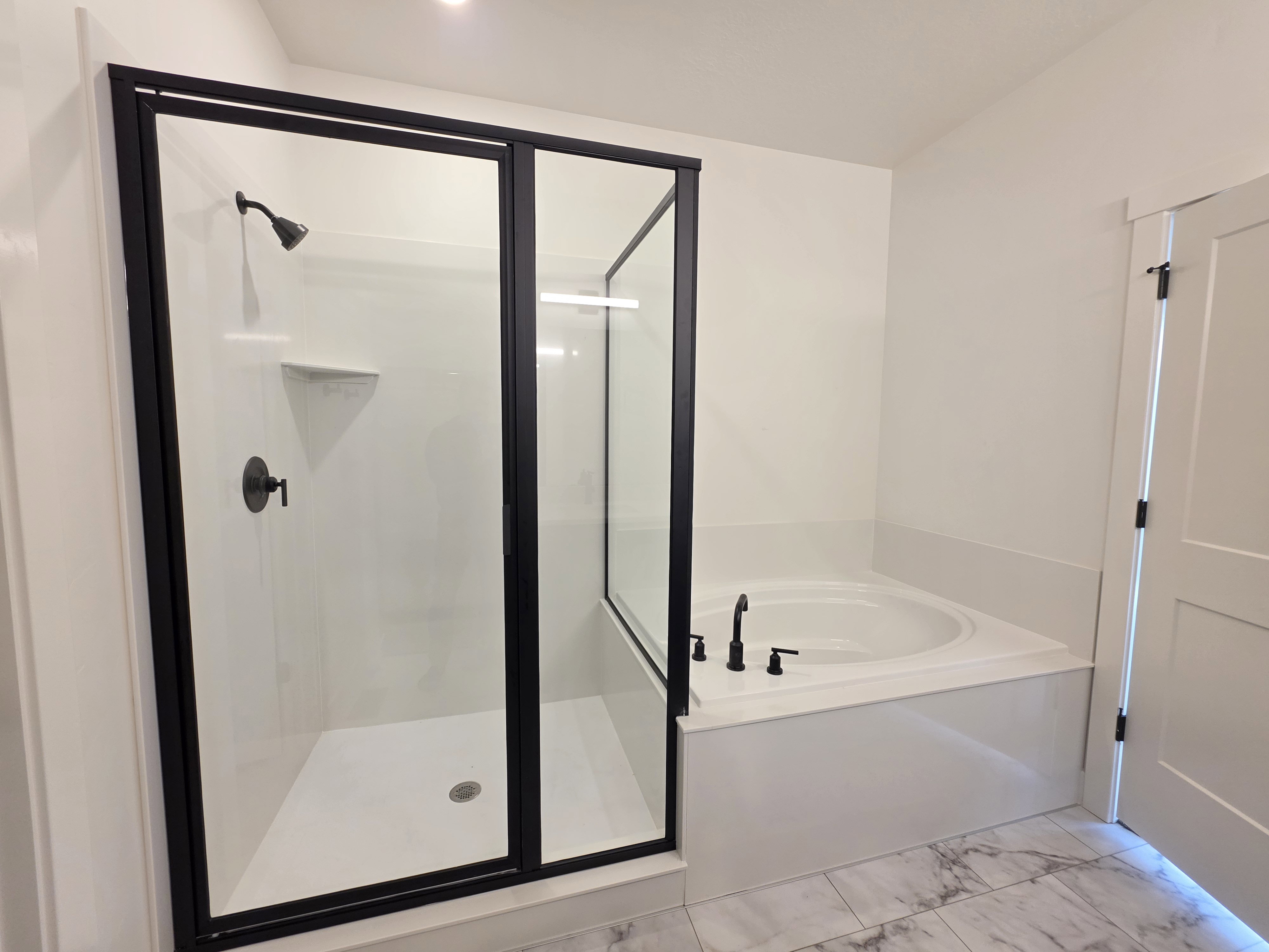 Contemporary bathroom featuring a walk-in shower with black-framed glass enclosure, built-in shower niche, and matte black fixtures